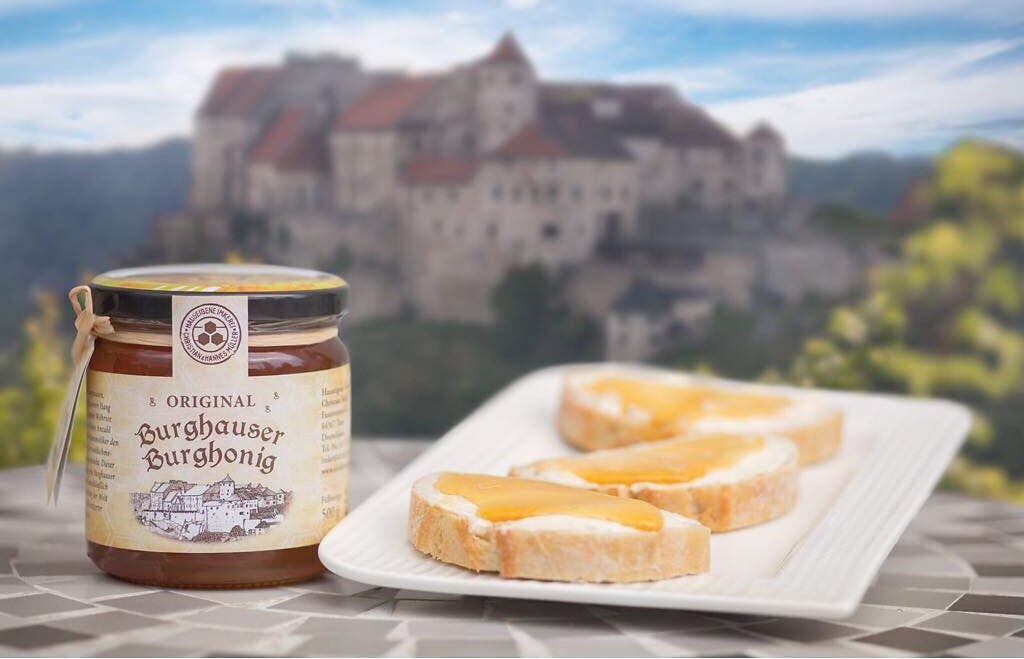 Honigglas und Honigbrot und im Hintergrund die Burg Burghausen, © Alztalhonig Honigglas und Honigbrot und im Hintergrund die Burg Burghausen, © Alztalhonig