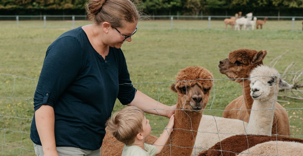 Mama und Kind streicheln Alpakas, © Inn-Salzach Tourismus Mama und Kind streicheln Alpakas, © Inn-Salzach Tourismus