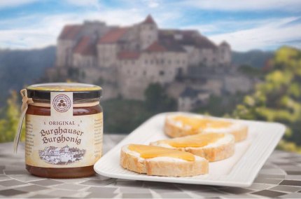 Honigglas und Honigbrot und im Hintergrund die Burg Burghausen, &copy; Alztalhonig