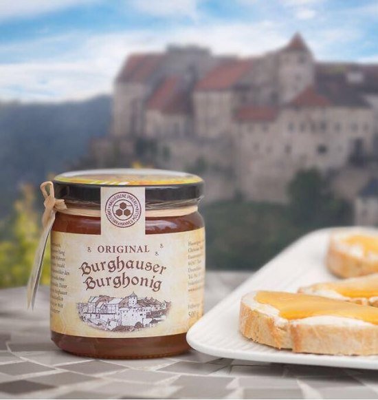 Honigglas und Honigbrot und im Hintergrund die Burg Burghausen, &copy; Alztalhonig