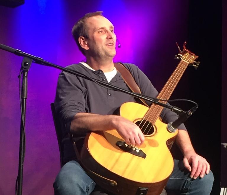 Tom Brückner sitzt auf einem Stuhl mit einer Gitarre, © Tom Brückner