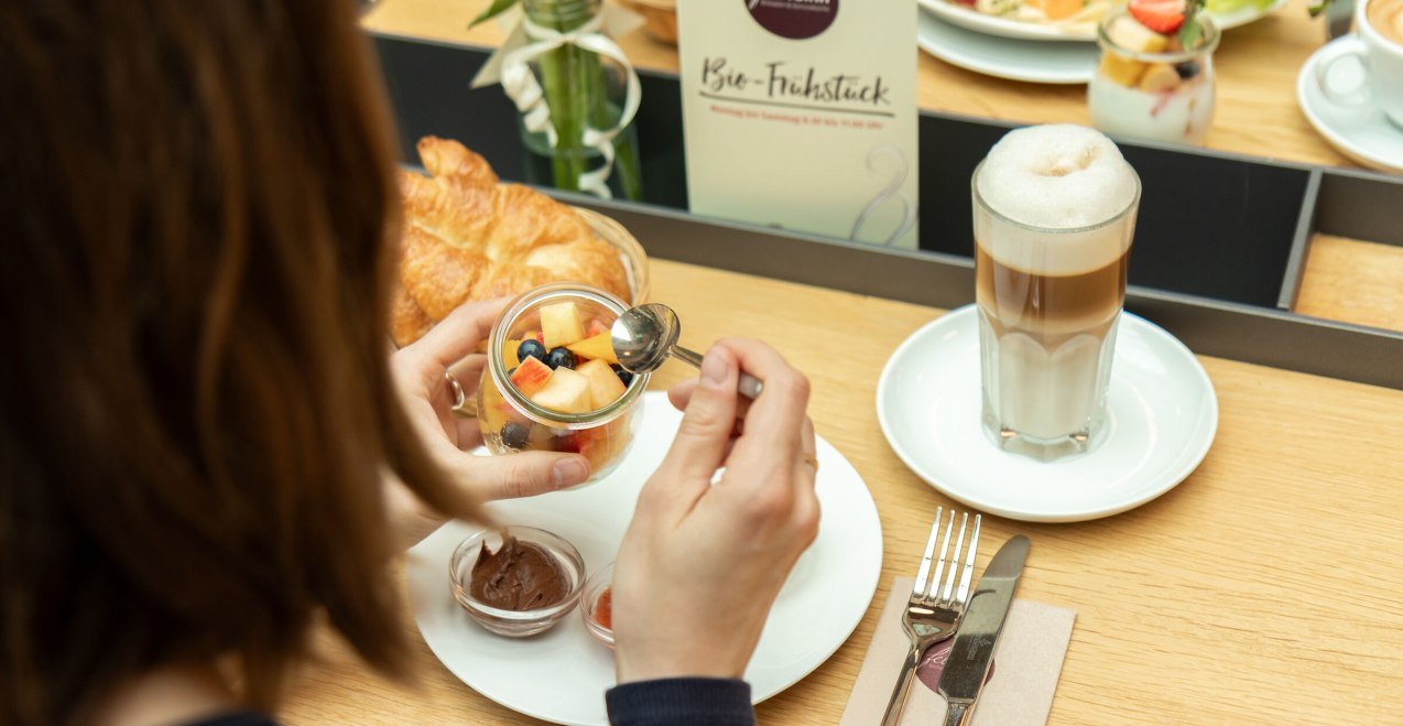 Müsli mit Obst und dazu einen Kaffee Latte, © Feinsinn - Bioladen & Genussküche