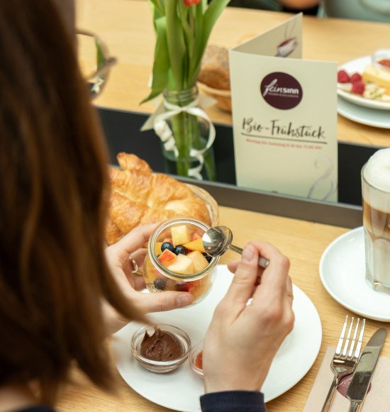 Müsli mit Obst und dazu einen Kaffee Latte, © Feinsinn - Bioladen & Genussküche
