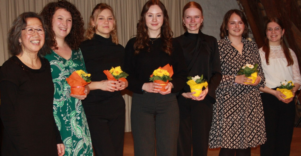 Sieben Frauen, wovon die meisten eine Blume halten schauen freundlich in die Kamera, © Katharina Röhrl