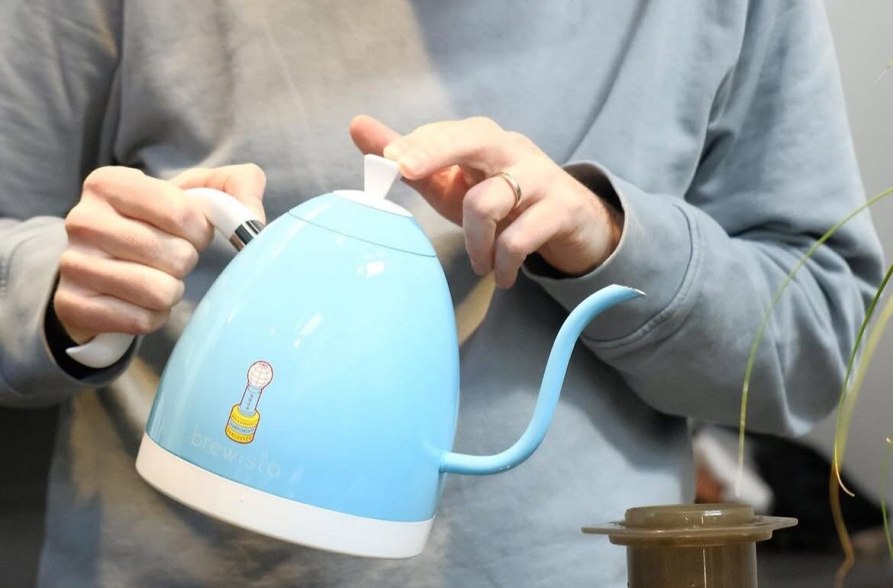 Ein Barista hält einen blauen Brewista-Wasserkocher und bereitet konzentriert eine AeroPress-Zubereitung vor – mit Liebe zum Detail und modernem Kaffeehandwerk., © ertl.kaffee