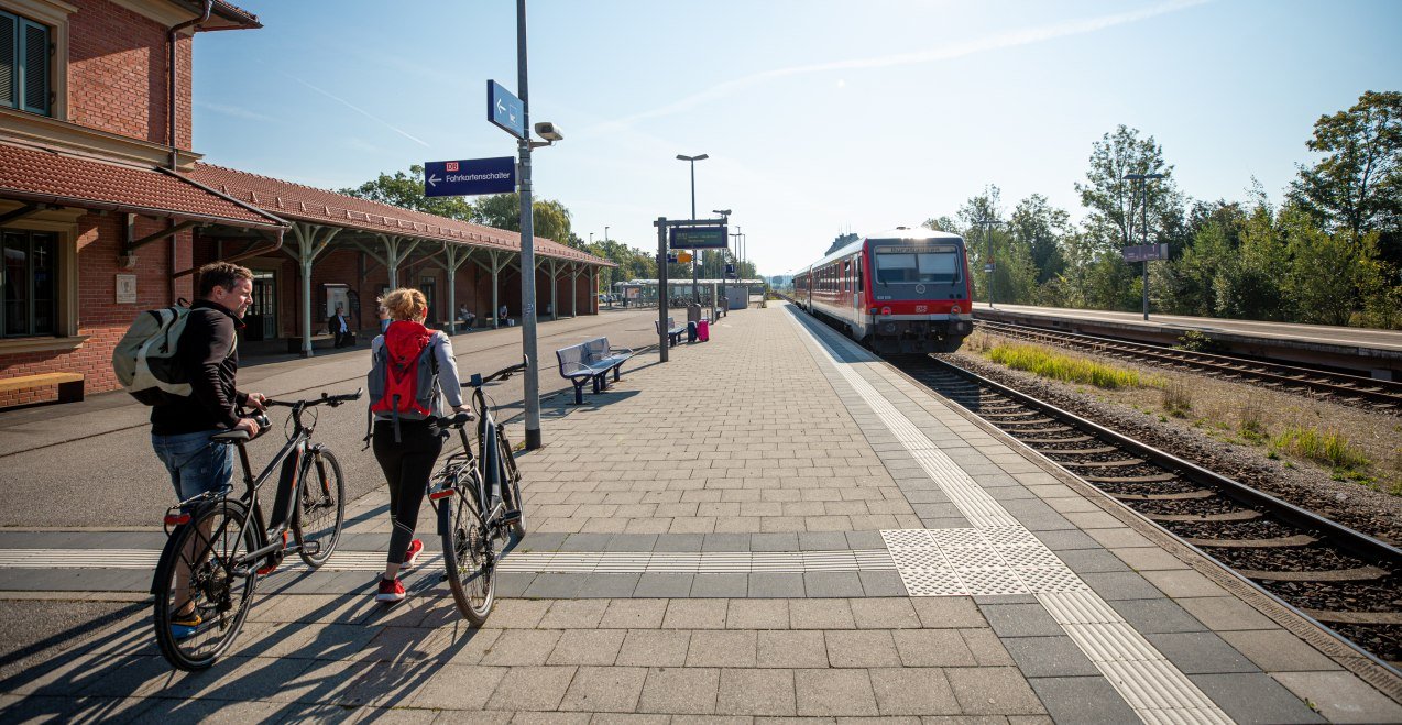 Zwei Radfahrer reisen am Bahnhof Altötting an.