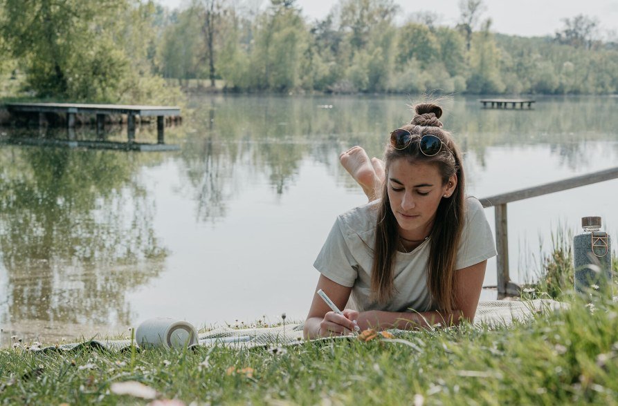 Frau liegt auf der Wiese des Peracher Badesees, © Inn-Salzach Tourismus